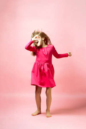 Funny dancing little girl. Real emotions and expression. Pink palette. The concept of childhood, fun, childrens party, holiday.の写真素材