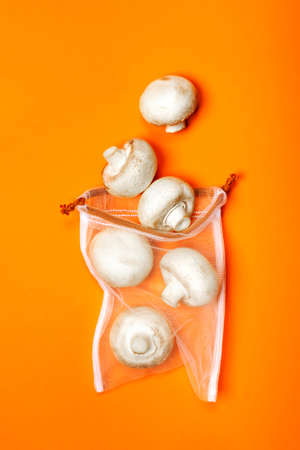 Cute organic champignons in the eco bag on a trendy orange background. Zero waste concept, plastic-free, eco-friendly shopping, veganの写真素材