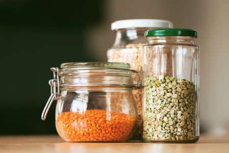 Glass jars with beans in the minimalistic interior. Peas and lentils as sources of vegetable...