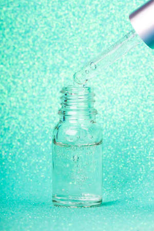 Face serum close-up on the trendy mint background. Collagen, hyaluronic acid for skin care. Achievements of modern science in cosmetic to preserve beauty.の写真素材