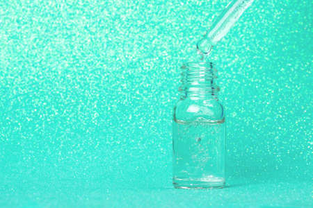 Face serum close-up on the trendy mint background. Collagen, hyaluronic acid for skin care....