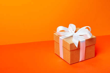 Trendy attractive minimalistic gift on the orange background. Merry Christmas, St. Valentines Day,...
