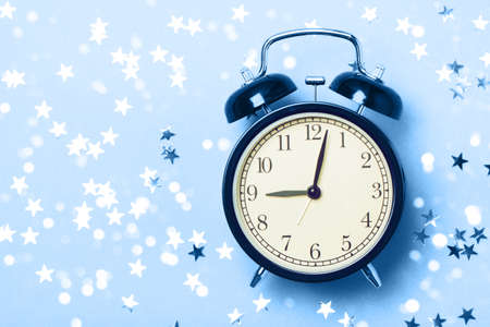 Alarm clock on a blue background with stars. The concept of preparing for sleep, an evening fairy...