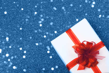 White box with a red ribbon on a festive blue background.