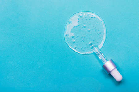 Face serum close-up on the trendy blue background. Collagen, hyaluronic acid for skin care....