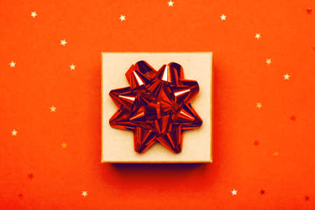 Attractive gift on a trendy orange background with stars. Present for St. Valentines day, weddings, engagements, Mothers Day, birthday, New Year, Christmas, holidaysの写真素材