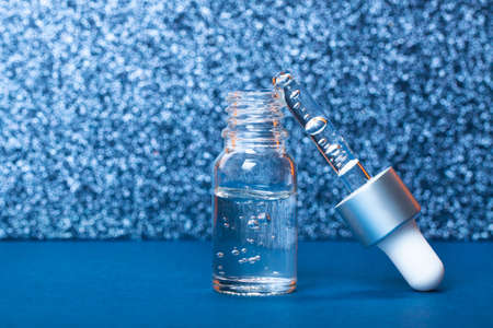 Face serum close-up on the trendy blue background. Collagen, hyaluronic acid for skin care....