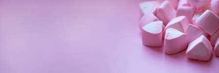 Heap of marshmallows in the shape of hearts on a pink background. Banner format. The concept of St....