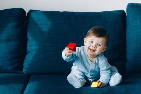 A cute little boy is playing on blue sofa. The concept of children games, entertainment in...