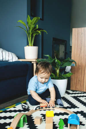A cute little boy is playing on the floor with cars. The concept of children games, entertainment in quarantine, stay home.の写真素材