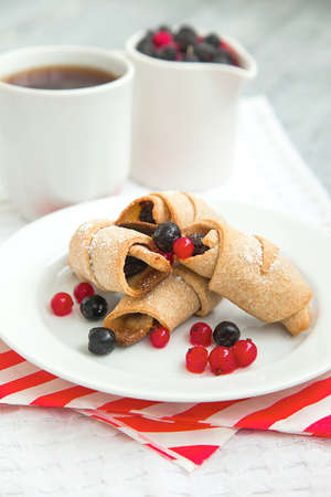 sweet bagels cookies and berries on a plate with two white cupsの写真素材