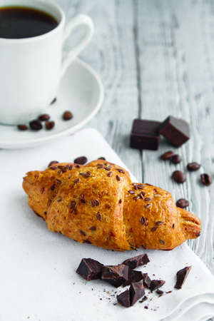 delicious croissant with a Cup of coffee on a wooden grey tableの写真素材