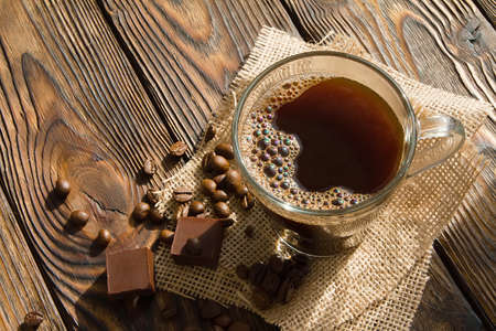 cup of espresso coffee and chocolate with scattered coffee beans on old wooden dark table early in the morningの写真素材