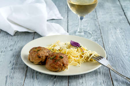 Hearty lunch from pasta spaghettii and a glass of white wine in a restaurantの写真素材