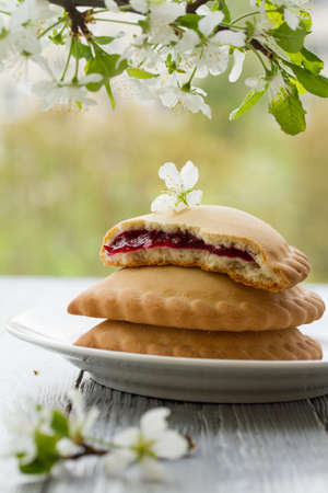 Cherry pies on saucer in spring composition on wooden background.Spring still life with cherry blossomsの写真素材