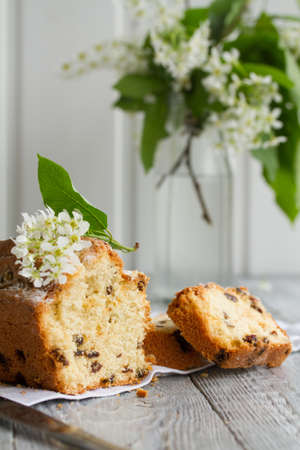 Homemade tasty cut cake with raisins and cherry flowers on a grey wooden tableの写真素材