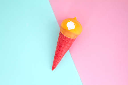 yellow ice cream in red waffle cone on trend blue pink background