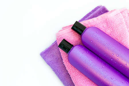 two purple cosmetic bottles on a bottles on two Spa bath towels on white backgroundの写真素材