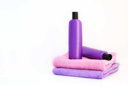 two purple cosmetic bottles on a bottles on two Spa bath towels on white background