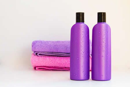 two purple cosmetic bottles on a bottles on two Spa bath towels on white backgroundの写真素材