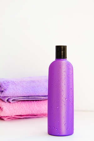 one purple cosmetic bottle on a bottles on two Spa bath towels on white backgroundの写真素材