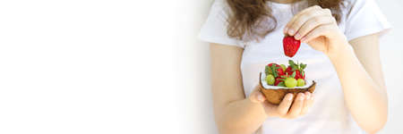 Healthy diet. Woman hands holding dessert of strawberries and grapes in half coconut