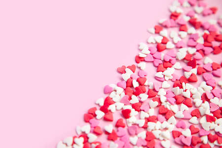 pink background and pink red sweet sprinkling hearts poured diagonal background
