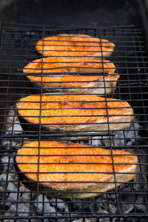 Salmon steaks cooking on barbecue grill for summer outdoor party. Food background with barbecue partyの写真素材