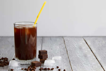 Ice coffee in a glass on gray wooden background