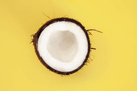 one half of ripe coconut on yellow background,top viewの写真素材