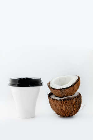 white Cup of drink and two halves of a ripe coconut on a white background