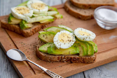 two avocado sandwiches with egg and spices on a wooden Boardの写真素材