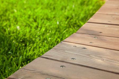 Wooden floor in diagonal on the image with blurred green grass background