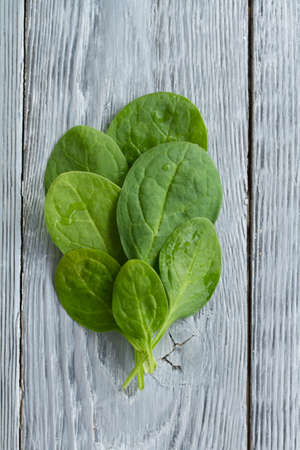 close - up of baby spinach sheets on wooden background,top view