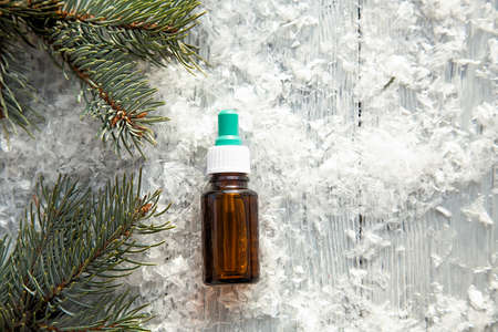 pine aroma oil extract natural in cosmetic bottle aromatherapy on winter snowy background
