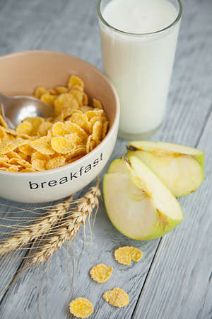 Healthy breakfast with glass of milk, apple and corn flakes. Top view, the wooden background
