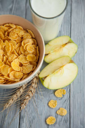 Healthy breakfast with glass of milk, apple and corn flakes. Top view, the wooden background