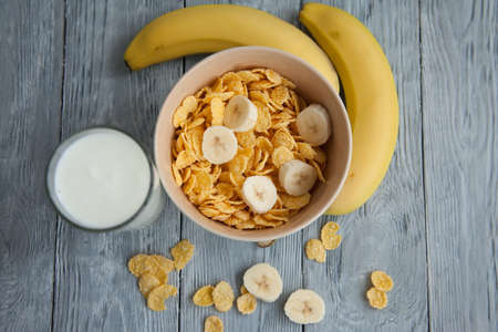 Healthy breakfast with glass of milk,bananas and corn flakes. Top view, the wooden background