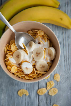 Healthy breakfast with glass of milk,bananas and corn flakes. Top view, the wooden background
