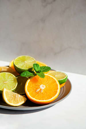 Plate of citrus fresh fruit and mint on a white table in sunlight. Concept summer food and drinkの写真素材
