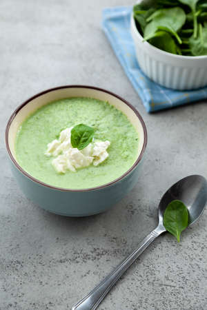 Green cream soup in a blue bowl on a stone gray table. Summer lunch or dinner.の写真素材