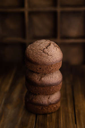 Chocolate homemade muffins stacked on a dark wooden table