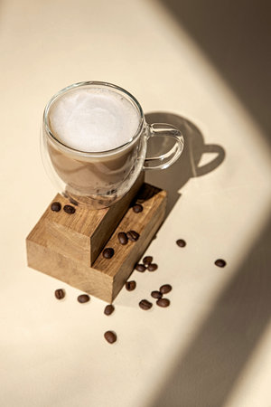 Glass cup of coffee on a beige background.Minimalist photo in daylight and shadow.の写真素材