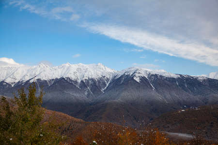 Autumn mountains with a snowy peak in blue skyの写真素材