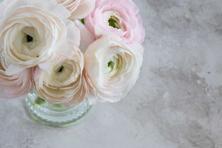 Bouquet of soft pink ranunculus flowers in a glass vase and gray table,top view.の写真素材