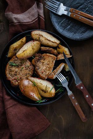 Fried potatoes with meat cut with a knife in a cast-iron frying pan with cutlery, top viewの写真素材