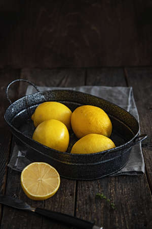 Lemons in an iron basin in a mood style and rustic.の写真素材