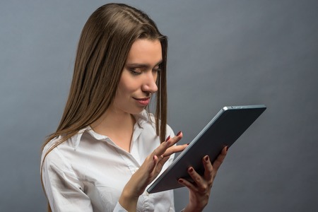 Business woman holding a tablet PC. on grey backgroundの写真素材