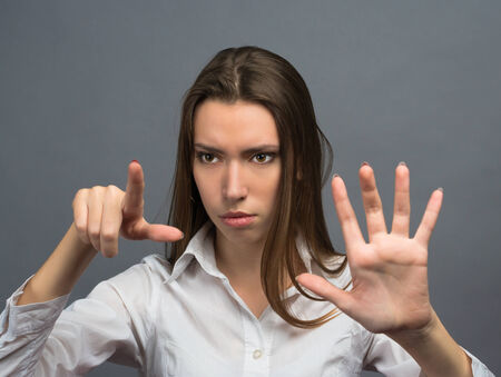 beautiful woman clicks on virtual touch screen on a gray backgroundの写真素材