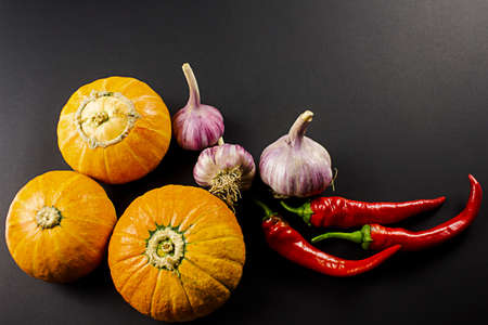 Three orange pumpkins close-up, capsicum, garlic on a black backgroundの写真素材